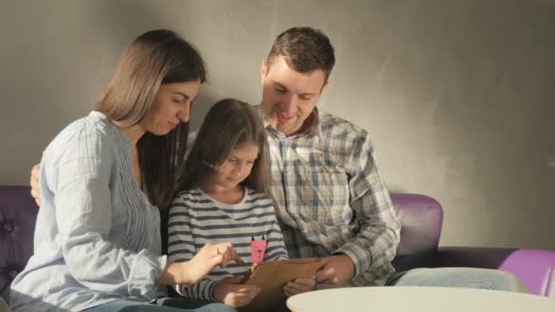 Jovem Mãe Filhinha Pai Sentados Sofá Roxo Salão Olhando Tablet — Vídeo de Stock