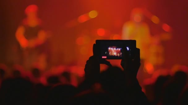 koncertní video, párty pro lidi, zatímco hudebníci hrají na jevišti, šťastní tančící dav, osoba nahrávací show na mobilním telefonu 