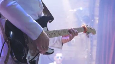 Gitarist konserde elektronik gitarla çalıyor. Gitarlı adam sahnede duruyor ve bir müzik çalıyor. Müzisyen rock konserinde gitar çalar. Kaya gitaristinin etrafında aydınlanma yanıp sönüyor.