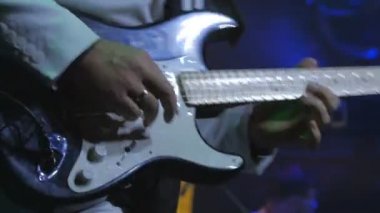 Gitarist konserde elektronik gitarla çalıyor. Gitarlı adam sahnede duruyor ve bir müzik çalıyor. Müzisyen rock konserinde gitar çalar. Kaya gitaristinin etrafında aydınlanma yanıp sönüyor.
