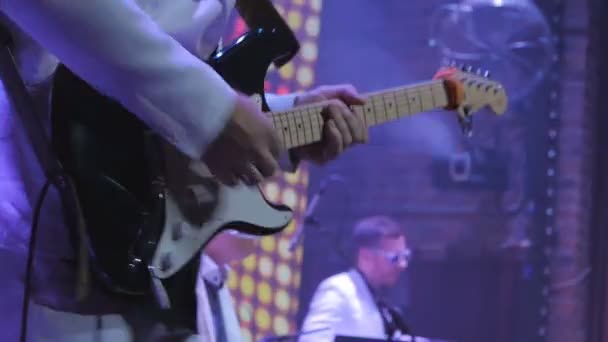 ギタリストはコンサートの電子ギターで演奏する ギターを持った男が現場に立ち音楽を演奏する ミュージシャンはロックコンサートでギターを演奏する ロックギタリストの周りに照明が点滅している — ストック動画