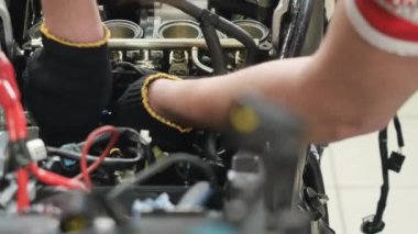 Motosikletin mühendis tamir motoru. Adam tornavidayla cevizi çeviriyor. Motosikletin içindeki ayrıntıları düzeltiyorum. Yakın plan. Kamera sağdan sola hareket eder.