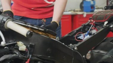 Mühendis motorun hava filtresini ayarlıyor. İşçi motosikleti tamir etti. Modern yol motosikletinin motorunu söküyorum. Yakın plan..