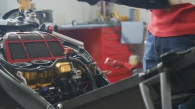 Mühendis motorun hava filtresini ayarlıyor. İşçi motosikleti tamir etti. Modern yol motosikletinin motorunu söküyorum. Yakın plan..