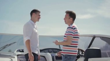 Satış elemanı yatı alıcıya veriyor. Genç adam yatın alımı ve özellikleri hakkında sorular soruyor. İş adamları yat satışı veya yat kiralamanın detaylarını tartışıyor.