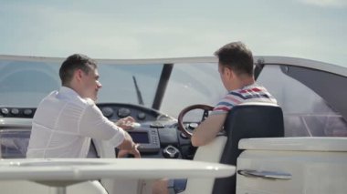 Satış elemanı yatı alıcıya veriyor. Genç adam yatın alımı ve özellikleri hakkında sorular soruyor. İş adamları yat satışı veya yat kiralamanın detaylarını tartışıyor.