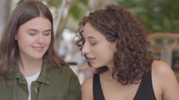 Portrét dvou dívek, které sedí v kavárně venku. Čas mladých děvčat spolu. Přátelský vztah. — Stock video