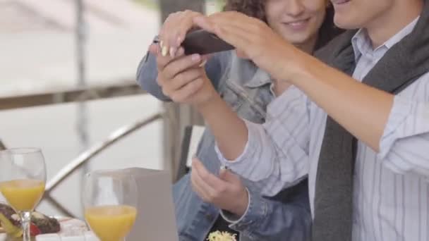 Jovem e mulher tirando fotos de sua comida usando celular no restaurante. O casal feliz desfrutando de seu jantar relaxando no café. Lazer juntos, conceito de data. Vício em gadgets — Vídeo de Stock