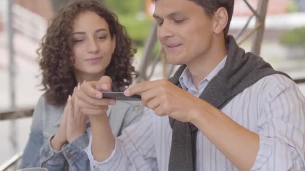 Hombre guapo y mujer linda tomando fotos de su comida usando el teléfono celular en el restaurante. La feliz pareja disfrutando de su cena relajándose en la cafetería. Ocio juntos, concepto de fecha. Gadget adicción — Vídeos de Stock