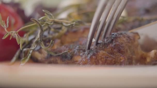 Close-up meat cutting with the knife and fork in the modern cafe or restaurant. Serving food in the cafe. Unrecognizable visitor enjoying his meal. Tasty food concept. Slow motion — Stock Video