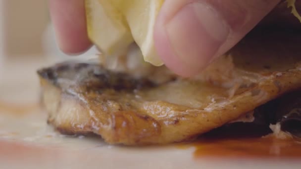 Primo piano di mano umana versando pezzo di pesce sdraiato sul piatto con succo di limone. Visitatore irriconoscibile che si gode il suo cibo di mare. Gustoso concetto di cibo. Rallentatore . — Video Stock