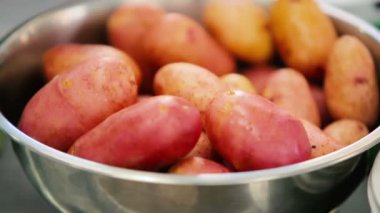 Yakın plan: Patates, turp, kabak. Kasedeki sebzeler. Restoranın mutfağındaki masada taze sebzeler var. Kamera aşağıdan yukarıya hareket eder.