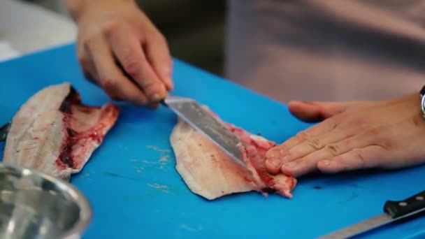 厨师在餐馆的厨房里准备鱼 人在刨花板上的鱼片上切刀鱼骨头 男人把骨头放进碗里 — 图库视频影像