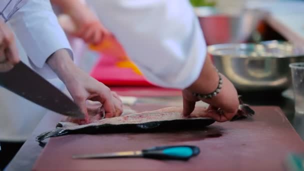 在餐馆厨房里准备鱼的女人 厨师教你如何在鱼片里切刀鱼骨头 雌性手在木板上割鱼 — 图库视频影像