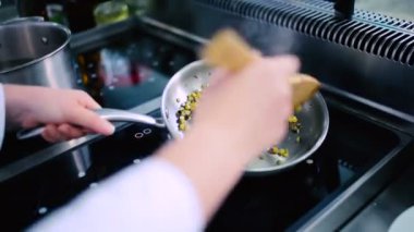 Mısır ve kabağı tavada kızart. Aşçı sebzeleri ahşap kaşıkla karıştırır. Aşçı bir tava götürür..