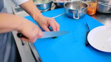 Aşçı tahtadaki kuşkonmazı küçük parçalara ayırıyor..