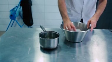 İnsan hamuru su ve undan yoğurur. Adam una su ekliyor ve hamur plastik bıçakla karıştırılıyor..