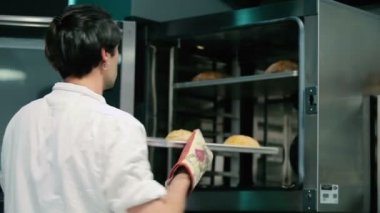 Aşçı sobanın tepsisindeki ekmeği alır. Adam masaya koydu..