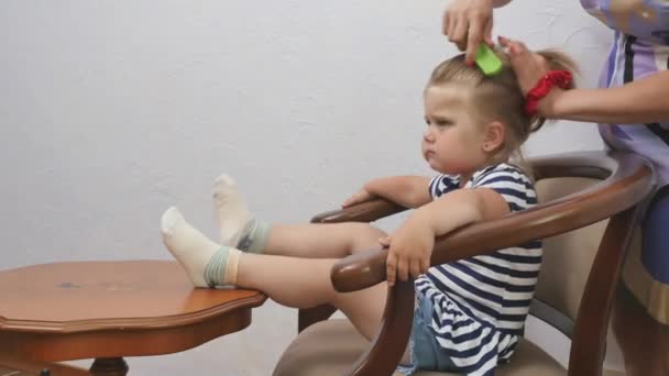 Küçük Kız Masanın Yanındaki Sandalyede Oturuyor Anne Kızının Saçını Tarar — Stok video