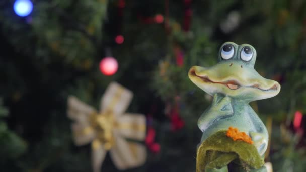 Leksaksgroda Snurrar Framför Kameran Julgran Med Julbollar Bakgrunden Närbild — Stockvideo