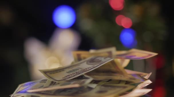 一百美元的钞票在摄像机前旋转着 背景上有圣诞球的圣诞树 后续行动 — 图库视频影像