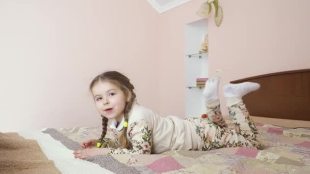 小女孩在家里的床上玩得很开心 可爱的孩子正在放松 沿着床移动 漂亮的女孩很无聊 自己玩 — 图库视频影像