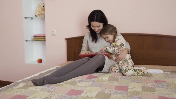 Giovane Madre Con Figlioletta Siede Sul Letto Casa Guarda Qualcosa — Video Stock