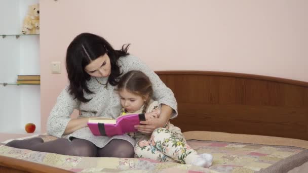 Mor Och Hennes Förtjusande Dotter Läser Boken Tillsammans Sittandes Sängen — Stockvideo