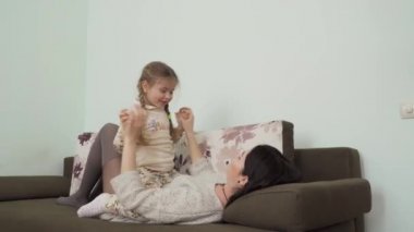 Küçük tatlı kızı olan genç bir anne evdeki kanepede dinleniyor. Mutlu bir aile, boş zamanlarını birlikte geçirir. Sevgili anne ve çocuğu oturma odasındaki kanepede yatıyorlar..