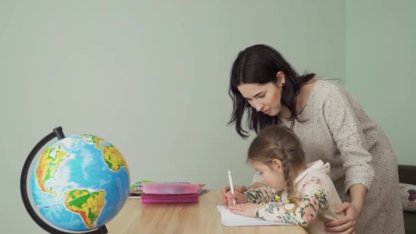 Moeder Helpt Haar Dochtertje Thuis Huiswerk Maken Jonge Vrouw Toont — Stockvideo