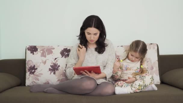 Mãe Jovem Com Filha Pequena Senta Sofá Casa Usa Tablet — Vídeo de Stock