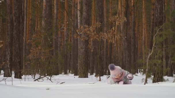 可爱的小女孩在冬天的森林里散步 爱玩的孩子一个人在雪地里玩得很开心 迷人的女孩在雪地上爬行 慢动作 Prores Codec — 图库视频影像