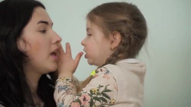 Anne ve kızı birbirleri ile sırlarını paylaşırlar. Kız annenin kulağına bazı kişisel bilgiler fısıldıyor. Güzel kız sırlarını annesine emanet eder. Yakın plan. Yavaş çekim.