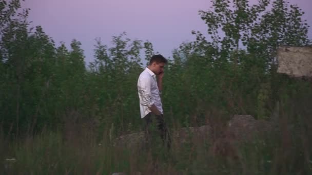 Young Man White Shirt Walking Talk Phone Thickets Grass Male — Stock Video
