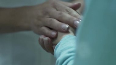 Tanınmayan kadın doktor küçük hastanın ellerine masaj yapıyor, çocuğu sakinleştiriyor. Sağlık, tedavi, rekreasyon, tıp kavramı. Çocuk doktoru çocuğu muayene ediyor