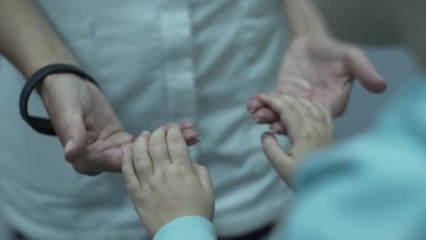 Ręce młodej kobiecej lekarza trzymające ręce małego pacjenta, uspokajające ją. Koncepcja opieki zdrowotnej, leczenia, rekreacji, medycyny. Pediatra bada dziecko — Wideo stockowe
