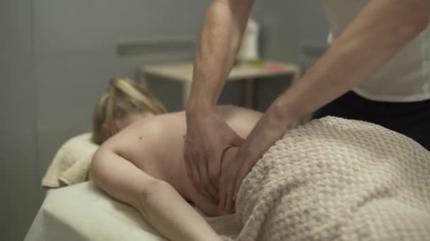 Nahaufnahme männlicher Hände, die der jungen Frau den Rücken massieren. Mädchen beim Massagetherapeuten. Konzept der Gesundheitsfürsorge, Behandlung, Erholung, Medizin. Rückenprobleme. Seitenansicht — Stockvideo