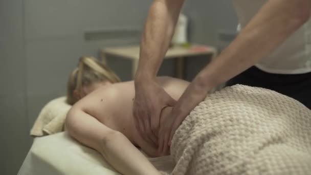 Fechar-se de mãos masculinas que massageiam atrás da mulher jovem. Rapariga do massagista. Conceito de cuidados de saúde, tratamento, recreação, medicina. Problemas com as costas. Vista lateral — Vídeo de Stock