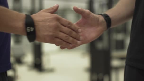 ジムのフィットネス機器の前に立って握手をする2人の選手。スポーツ、アクティブライフスタイル、ヘルスケアの概念 — ストック動画