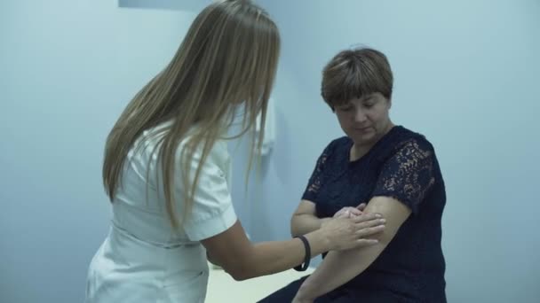Profesjonalny sukces kaukaski lekarz kontroli ramię starszej kobiety siedzi w biurze. Starsza pani sprawdzanie jej zdrowia w szpitalu. Koncepcja opieki zdrowotnej, leczenia, medycyny, rekreacji — Wideo stockowe
