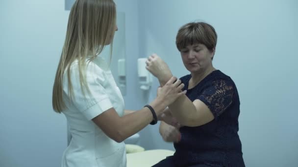 Médico caucásico profesional revisando el brazo de una anciana sentada en el consultorio. Dama madura comprobando su salud en el hospital. Concepto de salud, tratamiento, medicina, recreación — Vídeos de Stock