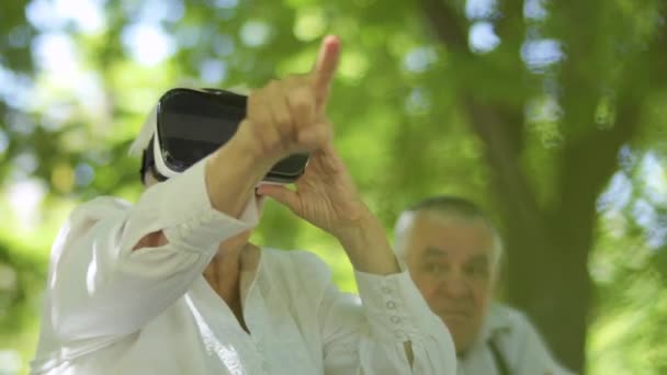在公园里使用虚拟现实眼镜的成熟女人 老太婆让她的丈夫试图用现代眼镜 — 图库视频影像