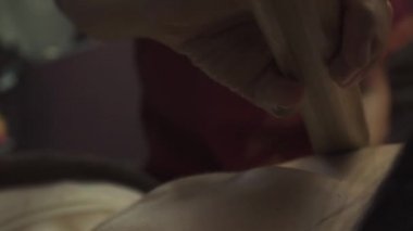 Tahta spa yatağında yatan genç bir kadının bambu vücut masajı çubukları var. Yakın plan..