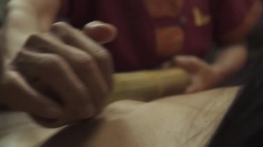 Tahta spa yatağında yatan genç bir kadının bambu vücut masajı çubukları var. Yakın plan..
