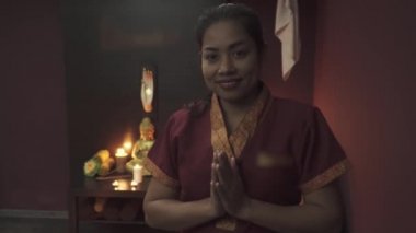Masaj salonunda gülümseyen güzel Tayland masözü. Kamera hareketi sağdan sola.
