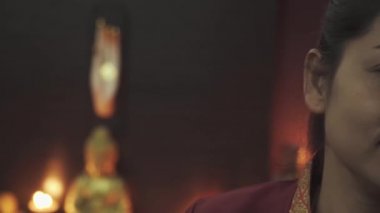 Taylandlı bir masözün etkileyici koyu gözleri. Masaj salonunda kırmızı sabahlık giymiş güzel bir genç kadın. Kamera soldan sağa kayıyor. Yakın plan..