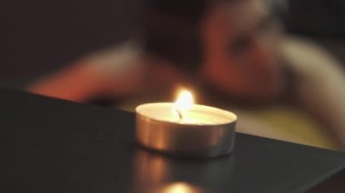 Masaj odasında, yalancı, güzel bir kızın önünde küçük bir mum yanıyor. Yakın plan..