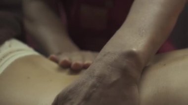 Masaj müşterisi sırt ve omuzlarına yağ sürmüş. Bir masözün elleri oğlanın derisinde. Muazzam bir Tayland masajı alan bir spa müşterisi. Yakın plan..