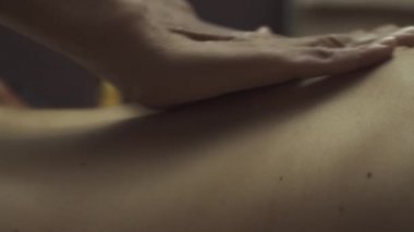 Masözün elleri kızın arkasını ve yanlarını okşuyor. Taylandlı bir masözden sağlam bir sırt masajı. Yakın plan..