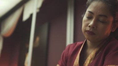 Kırmızı cüppeli güzel Tayland masözü bir erkeğe masaj yapıyor.